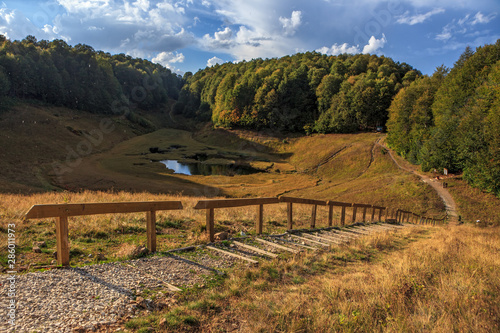 Bolshoye Khmelevskoye mountain lake surrounded with autumn Caucasus mountain forest at sunset. Beautiful scenic blue sky landscape. Krasnaya Polyana, Sochi, Russia photo