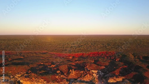 Scenic panoramic aerial drone view at sunset of flight high above ocean and remote beach in Western Australia, with rocky cliff coastline, summer sunny blue sky and horizon as background and copy spac