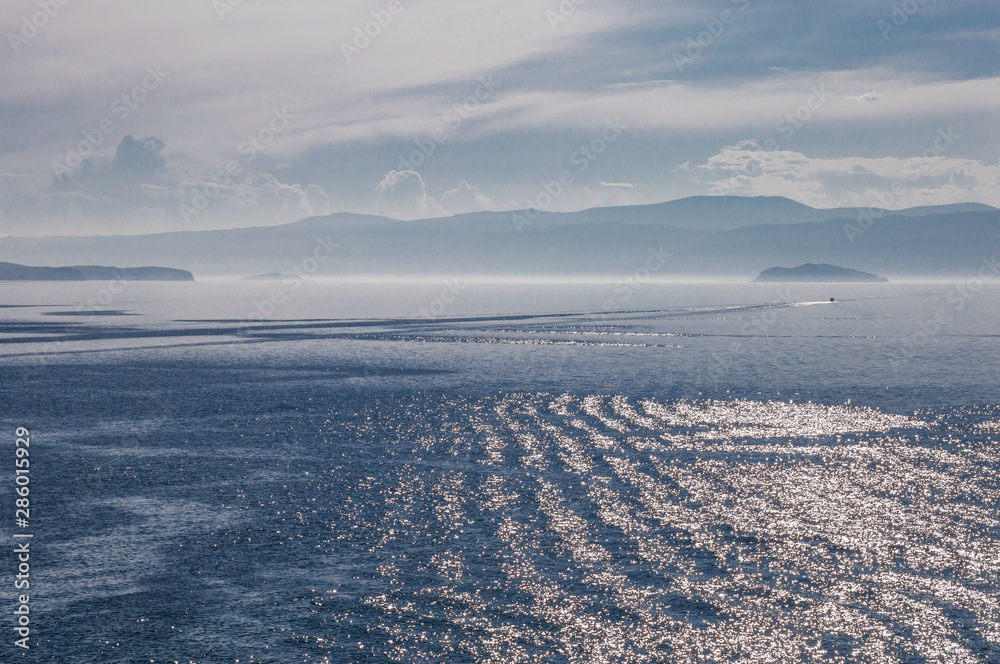 Obraz premium Lake Baikal in the afternoon light. Glare of sunlight on the surface of lake Baikal. Beautiful picture of lake Baikal. Russia. Siberia. Baikal. Olkhon Island.