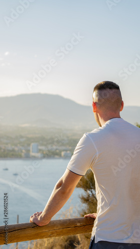 Hombre mirando una ciudad marítima con nostalgia