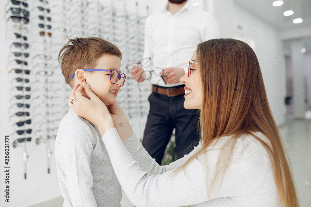 Mother with cute son. Family buy glasses. Assistant helping the clients Mother with cute son. Family buy glasses. Assistant helping the clients