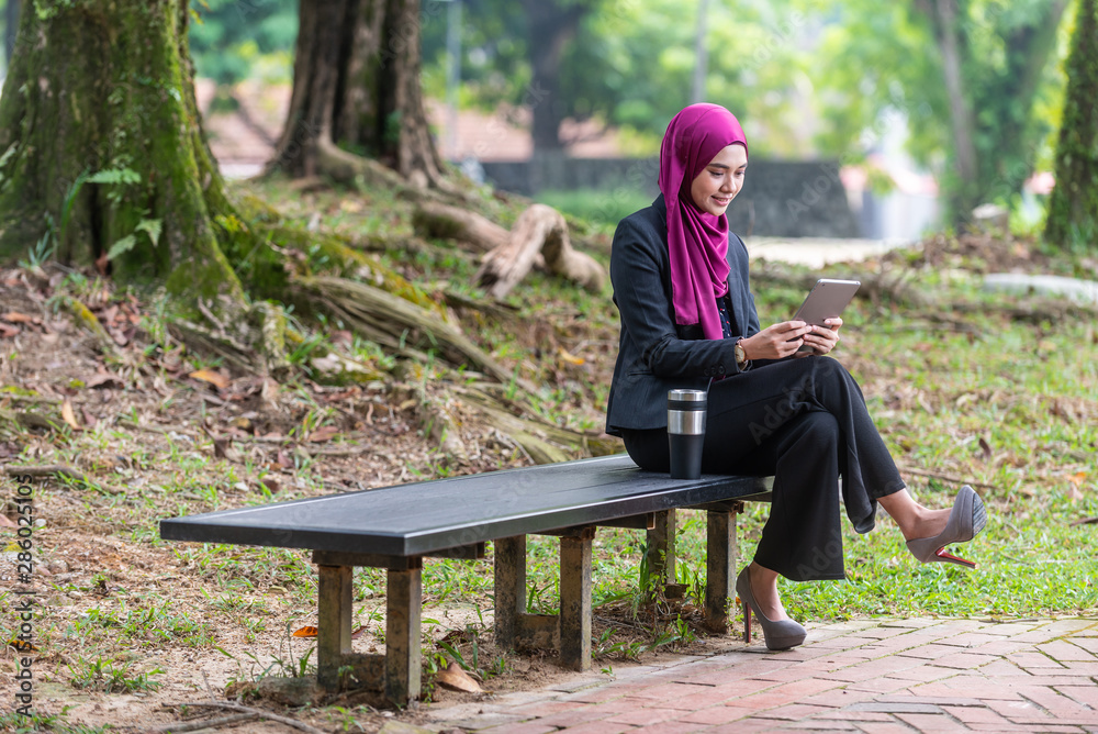 Fototapeta premium Muslim Businesswon on her table during a coffee break. Outdoor setting at a park.