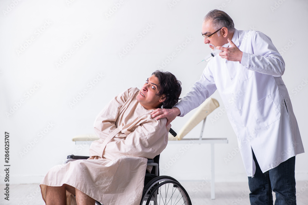 Obraz premium Old male doctor psychiatrist and patient in wheel-chair