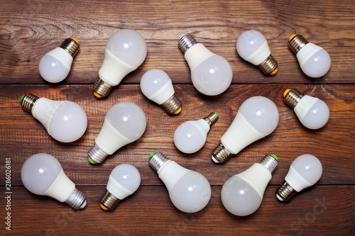 Several led bulbs of different sizes and different bases on a wooden background.
