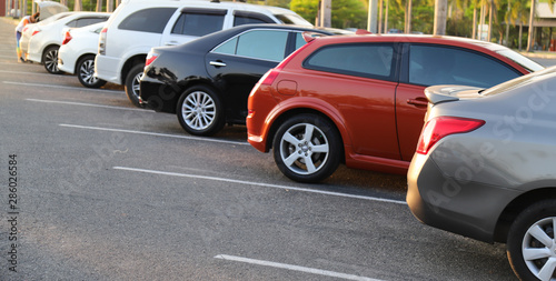Closeup of rear or back side of golden brown car with other cars parking in outdoor parking lot in twilight evening. 