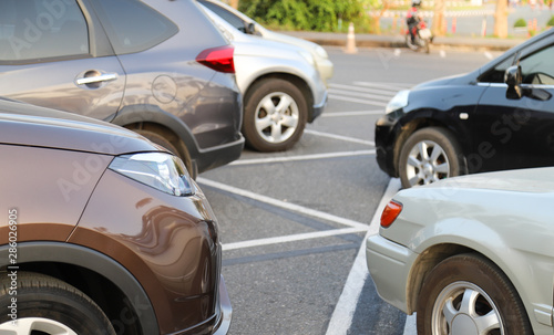 Closeup front side of brown car and other cars parking in outdoor parking lot in the evening. 