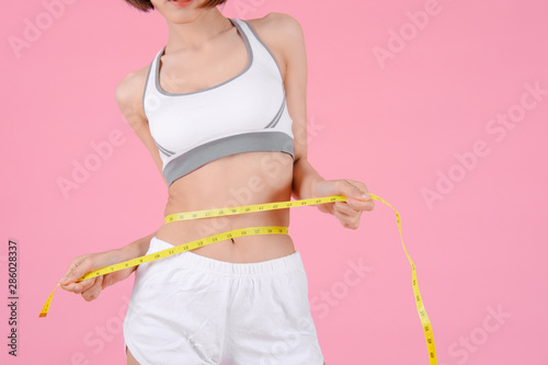 Healthy woman standing holdding tape measure and showing her beautiful body in home on pink backgrounds, Healthy concept, Diet concept © I Believe I Can Fly