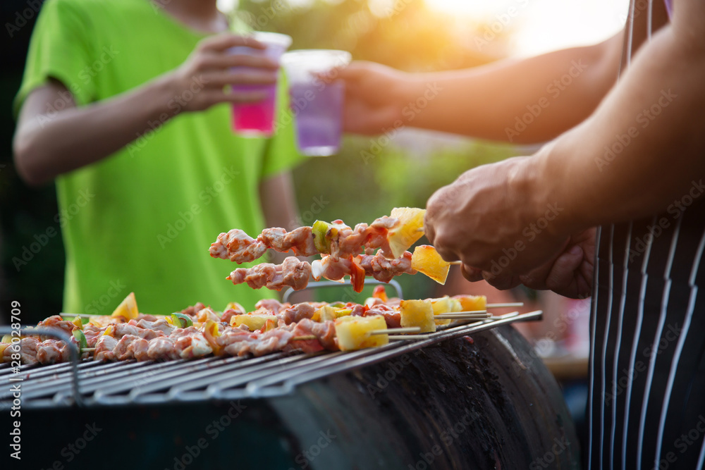 Man clinks drinks at a barbecue at an outdoor banquet.