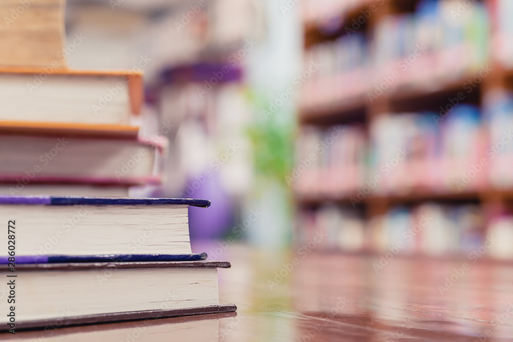 Textbook stack on wooden table with blur background of bookshelf in library with copy space. Photo concept of education, knowledge, traditional learning, and literature. Selective Focus Textbook stack on wooden table with blur background of bookshelf in library with copy space. Photo concept of education, knowledge, traditional learning, and literature. Selective Focus