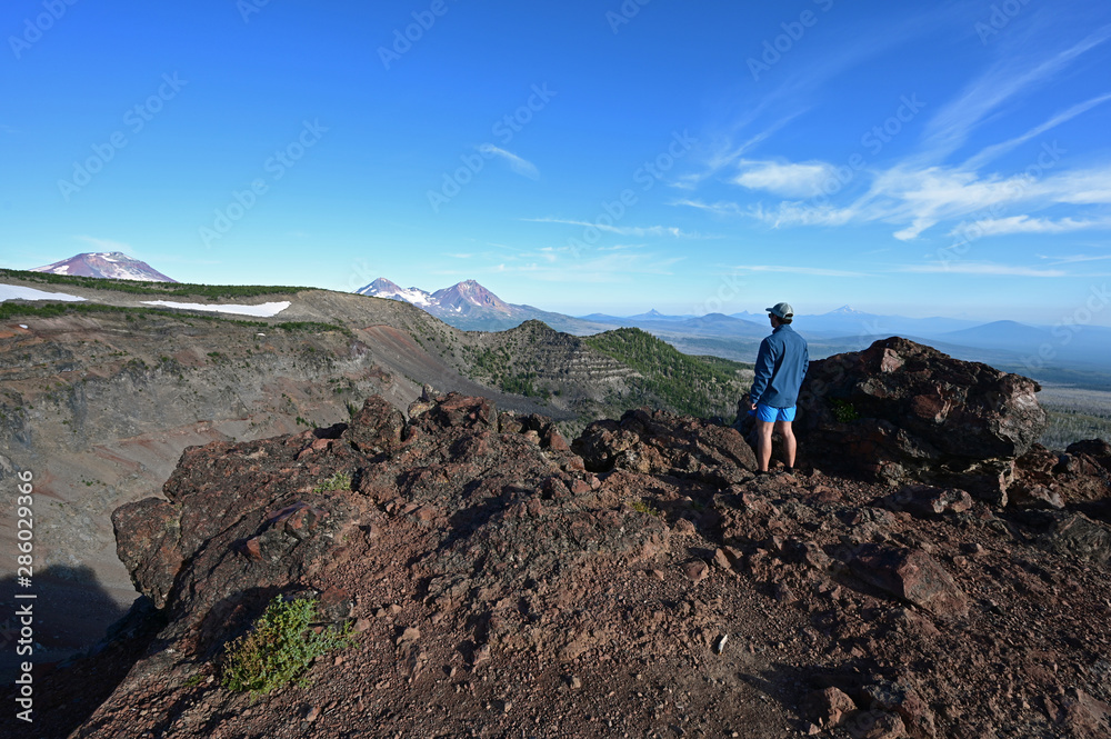 Young male trail runner enjoys view of Three Sisters volcanoes at end of Tam McArthur Trail in Three Sisters Wilderness, Oregon.