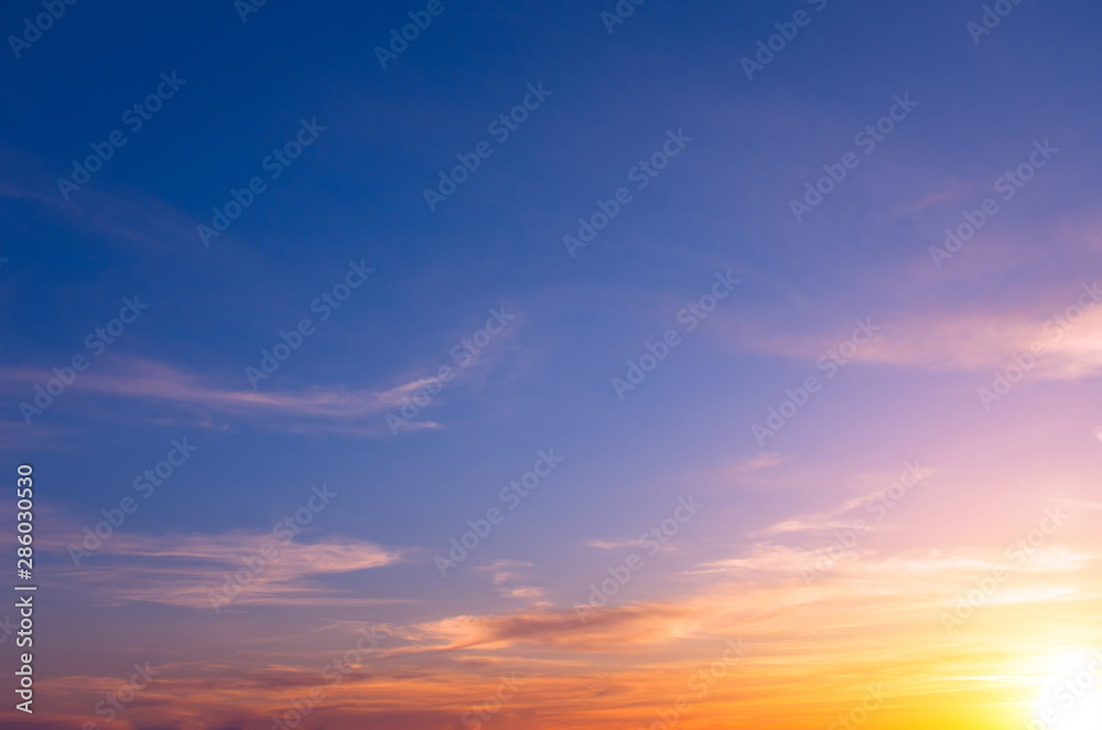 Bright sunset on a blue sky with bright sun and clouds.