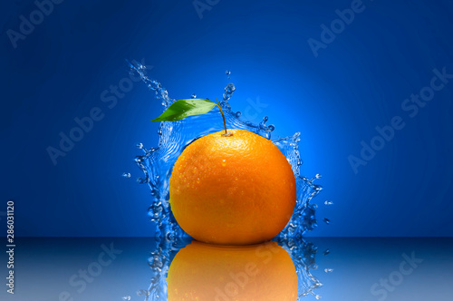 Fresh and healthy orange and water splash on blue background