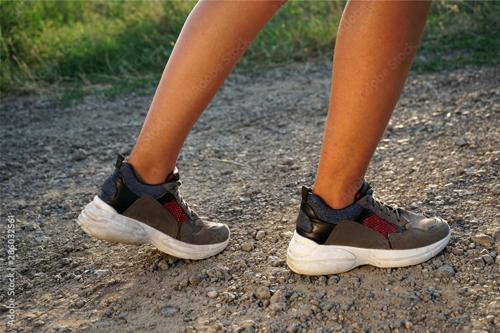Athlete runner feet running in nature, closeup on shoe. Woman fitness jogging, active lifestyle concept Athlete runner feet running in nature, closeup on shoe. Woman fitness jogging, active lifestyle concept