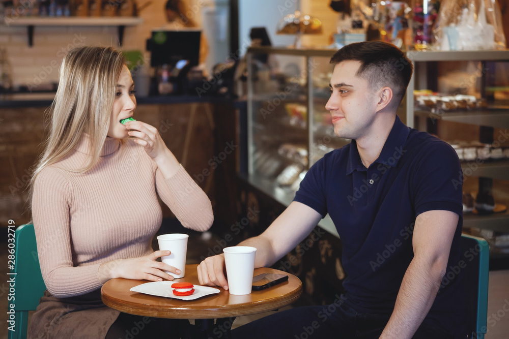 Two cute young students — boy and girl, sit in a cafe.