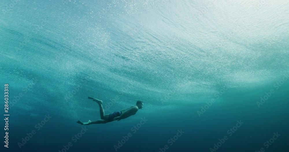 Man swimming beneath breaking ocean wave