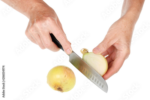 An old senior woman holds a onion bulb r in her hands and cuts it with a knife isolated photo