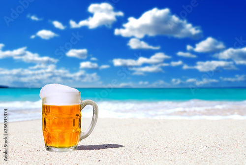 Beer in a glass mug on a white sand beach background