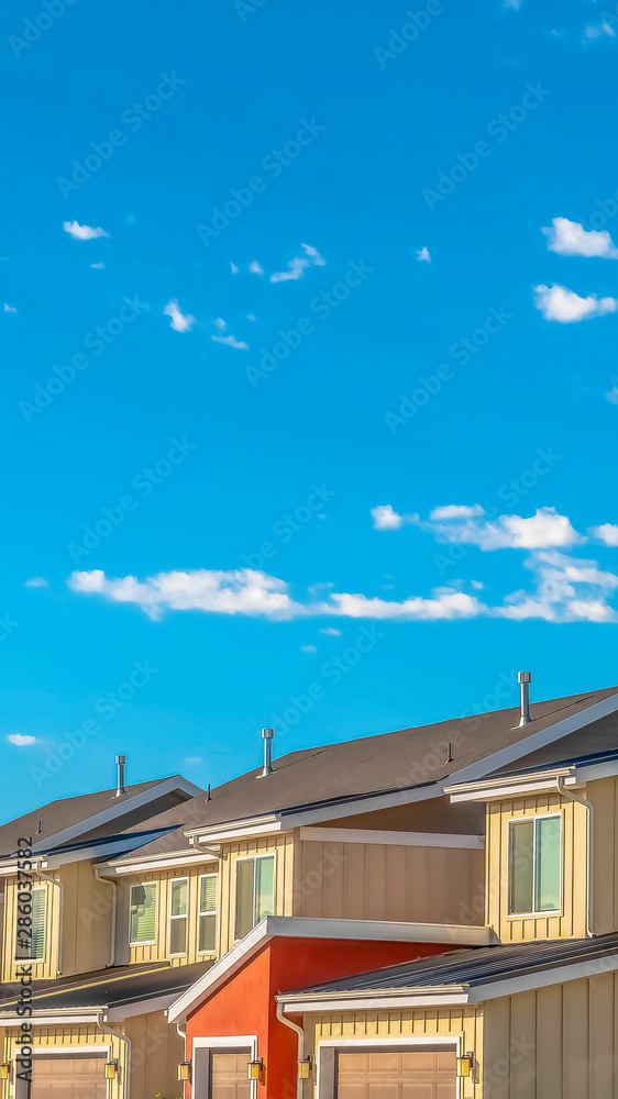 Vertical Home exterior with view of garages against blue sky and clouds on a sunny day Vertical Home exterior with view of garages against blue sky and clouds on a sunny day