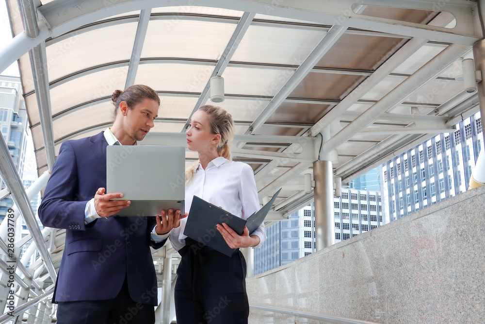 Portrait of two business partners looking together at report and laptop Portrait of two business partners looking together at report and laptop