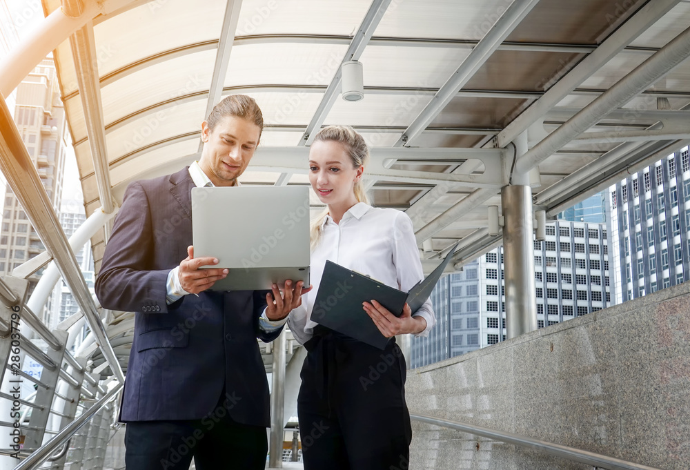 Portrait of two business partners looking together at report and laptop
