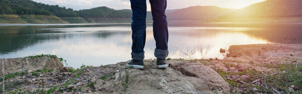 Freedom traveler standing with foot  and enjoying a beautiful nature. Image with sunlight effect filter