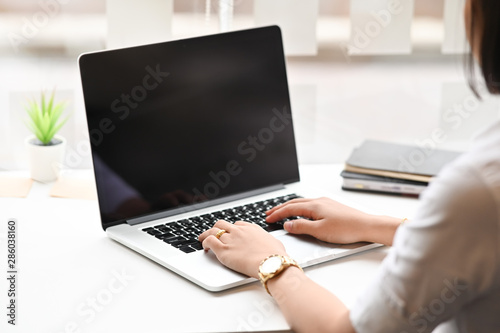 Young woman's typing laptop computer on table.