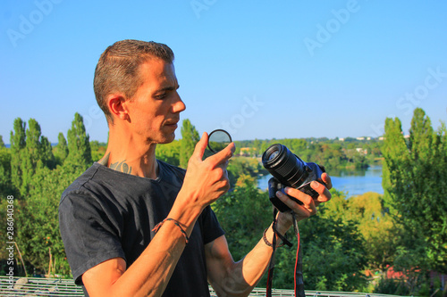 Quadro em tela Photographer man who installs a filter on his camera lens
