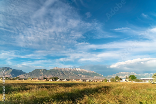 Scenic nature view with lush grassy field homes and towering snowy mountain photo