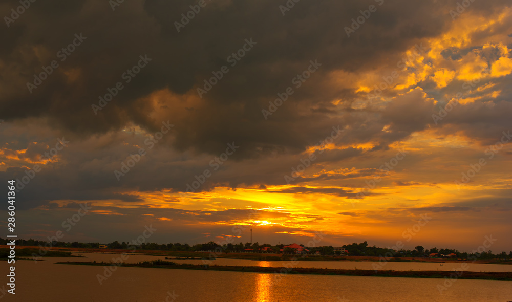 Beautiful Sunset in the sky with sky blue and orange light of the sun through the dark clouds in the sky, Orange and red dramatic colors - Image