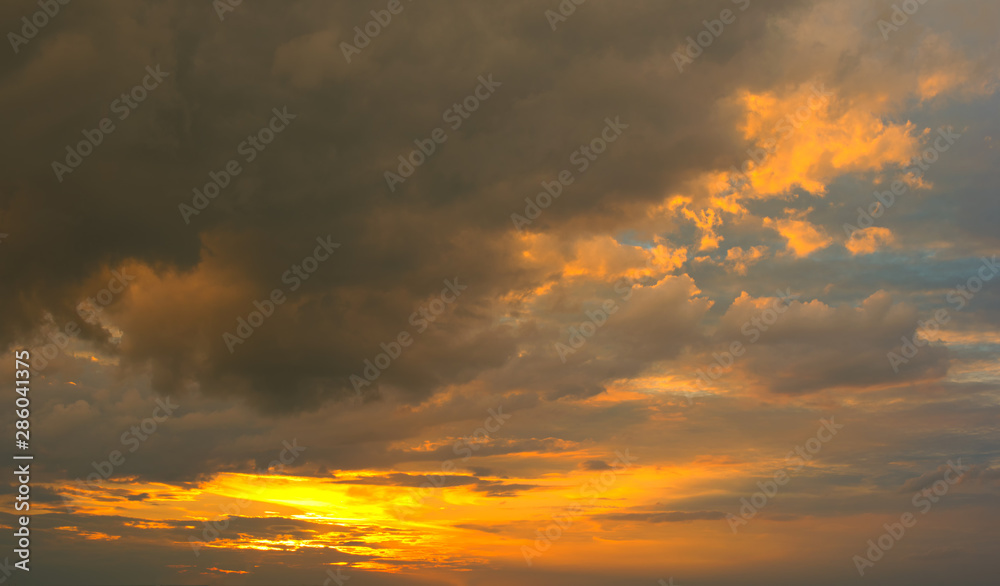 Beautiful Sunset in the sky with sky blue and orange light of the sun through the dark clouds in the sky, Orange and red dramatic colors - Image