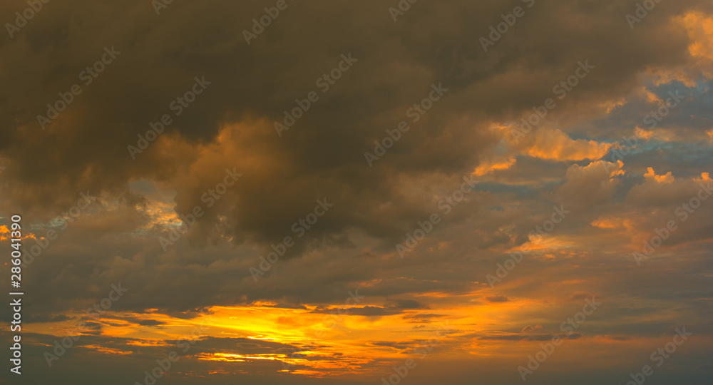 Obraz premium Beautiful Sunset in the sky with sky blue and orange light of the sun through the dark clouds in the sky, Orange and red dramatic colors - Image