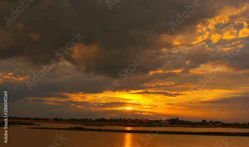 Beautiful Sunset in the sky with sky blue and orange light of the sun through the dark clouds in the sky  Orange and red dramatic colors - Image