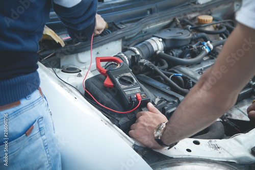Mechanic with a multimeter testing car engine. Car service