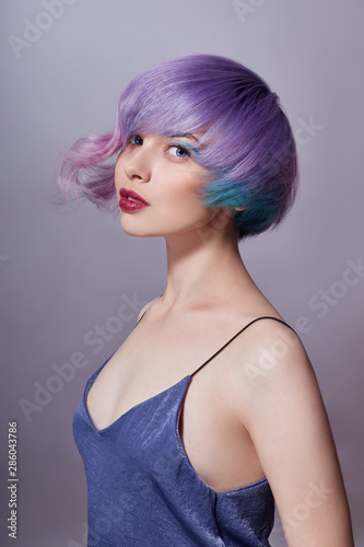 Portrait of a woman with bright colored flying hair, all shades of purple. Hair coloring, beautiful lips and makeup. Hair fluttering in the wind. Sexy girl with short hair. Professional coloring