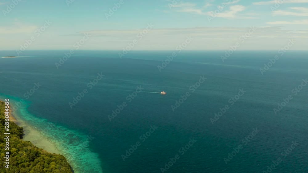 Small passenger ferry cruising in the open blue sea against blue sky with clouds, aerial view. Seascape: passenger ferry boat in open waters Philippines, Mindanao Small passenger ferry cruising in the open blue sea against blue sky with clouds, aerial view. Seascape: passenger ferry boat in open waters Philippines, Mindanao