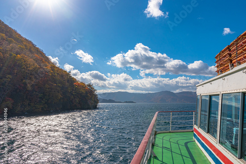 Lake Towada Sightseeing Cruises. Beautiful view, clear blue sky, white cloud, cruise ship in sunny day with autumn foliage season background. Towada hachimantai National Park, Aomori Prefecture, Japan