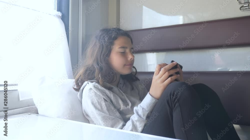 little girl walks on a train compartment car with and a smartphone. travel transportation railroad concept. the girl in the train at the window corresponds the girl in the train wagon at the window little girl walks on a train compartment car with and a smartphone. travel transportation railroad concept. the girl in the train at the window corresponds the girl in the train wagon at the window