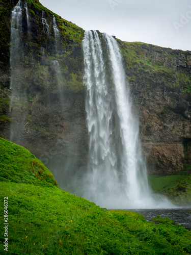 Skogafoss waterfall in green mountain landscape in Iceland