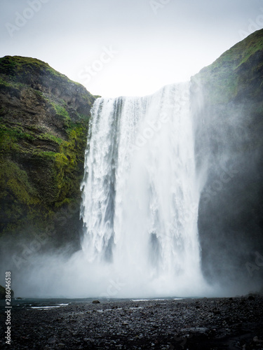 Skogafoss waterfall in green mountain landscape in Iceland