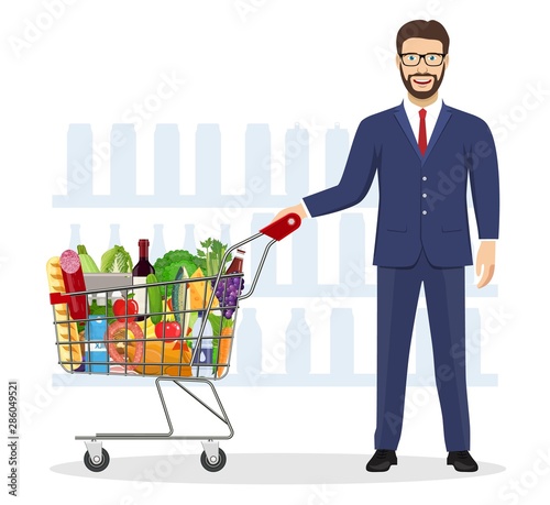 Young man pushing supermarket shopping cart full of groceries. Vector illustration in flat style