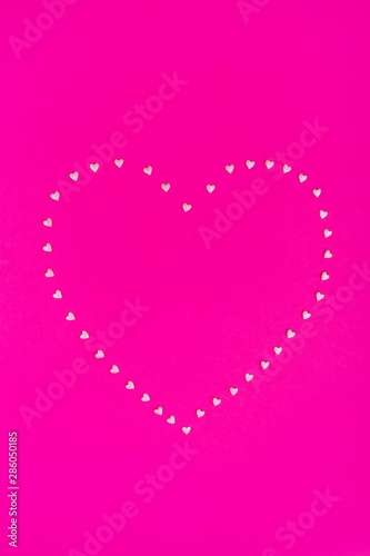 Pink confetti heart on bright pink background. Flat lay, top view, copy space.