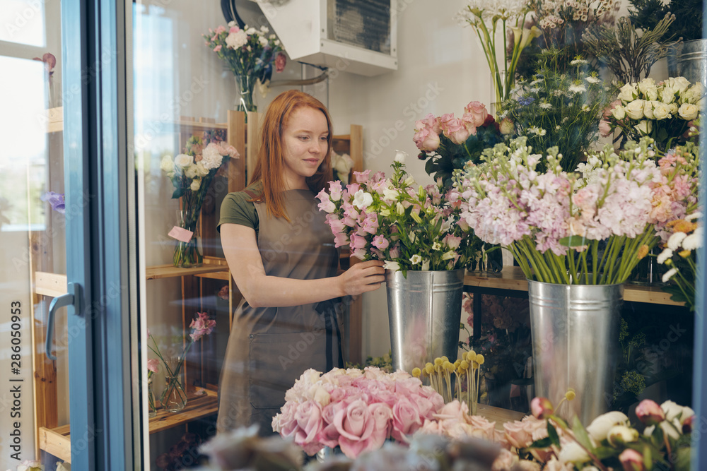 Young flower shop worker checking flowers