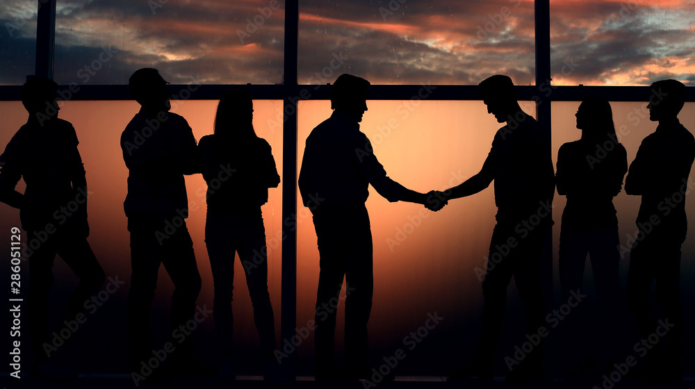 handshake two like-minded near a large window.