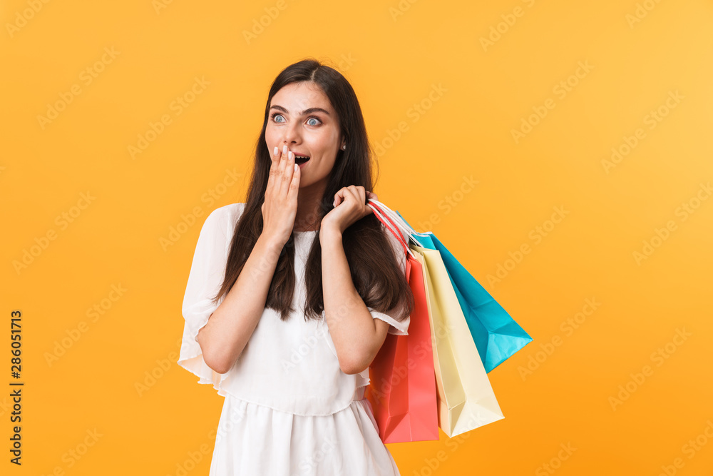 Portrait of excited shopaholic woman wearing dress looking at copyspace while holding colorful shopping bags Portrait of excited shopaholic woman wearing dress looking at copyspace while holding colorful shopping bags