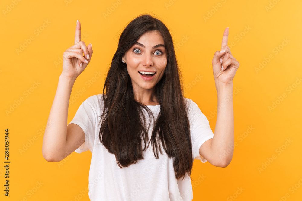 Image of beautiful brunette woman with long hair smiling and pointing fingers at copyspace Image of beautiful brunette woman with long hair smiling and pointing fingers at copyspace