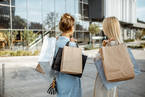 Two women holding empty shopping bags with copy space, while standing back near the shopping mall