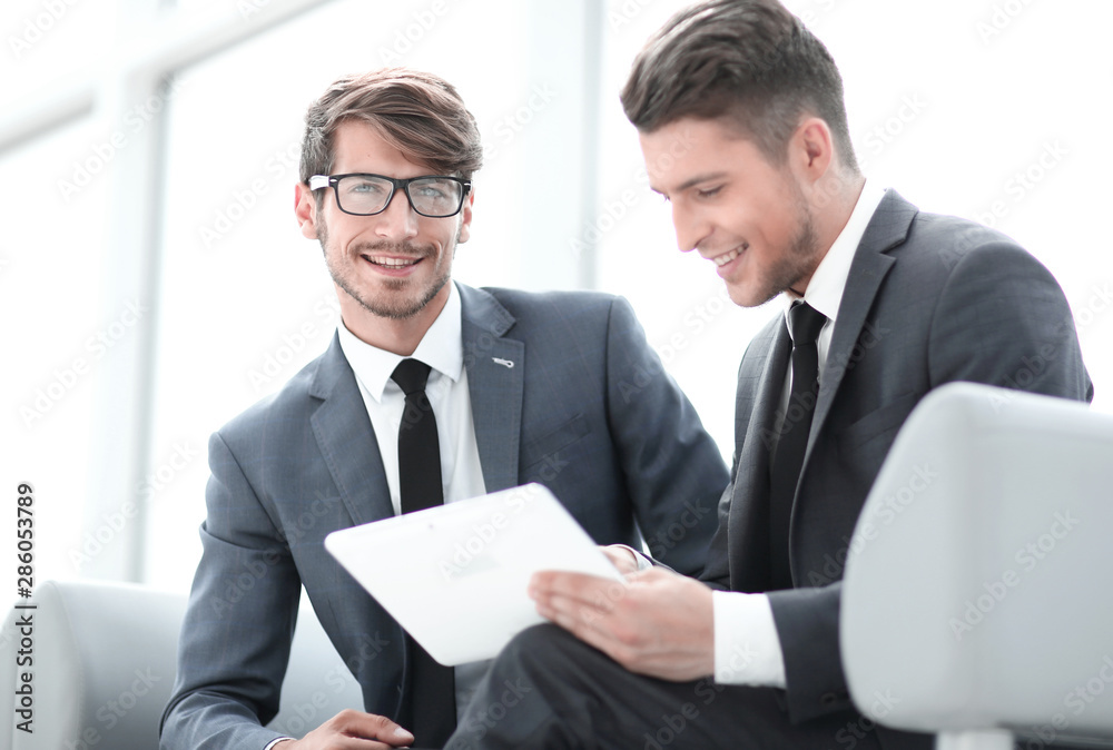 Two smiling elegant business people looking at something on digital tablet Two smiling elegant business people looking at something on digital tablet