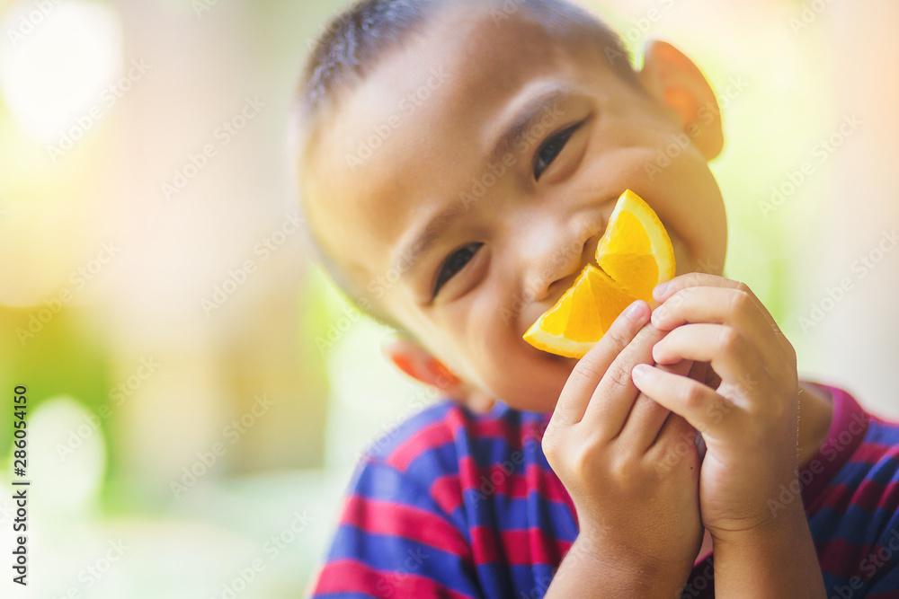 Little asian boy use a slice of orange for smiling face Little asian boy use a slice of orange for smiling face