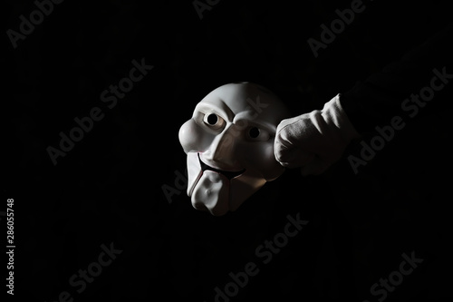 Foto White scary mask on a black background with whites hand.