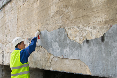 Bilde på lerret city worker clean walls of graphics and inscriptions, with a metal brush, before